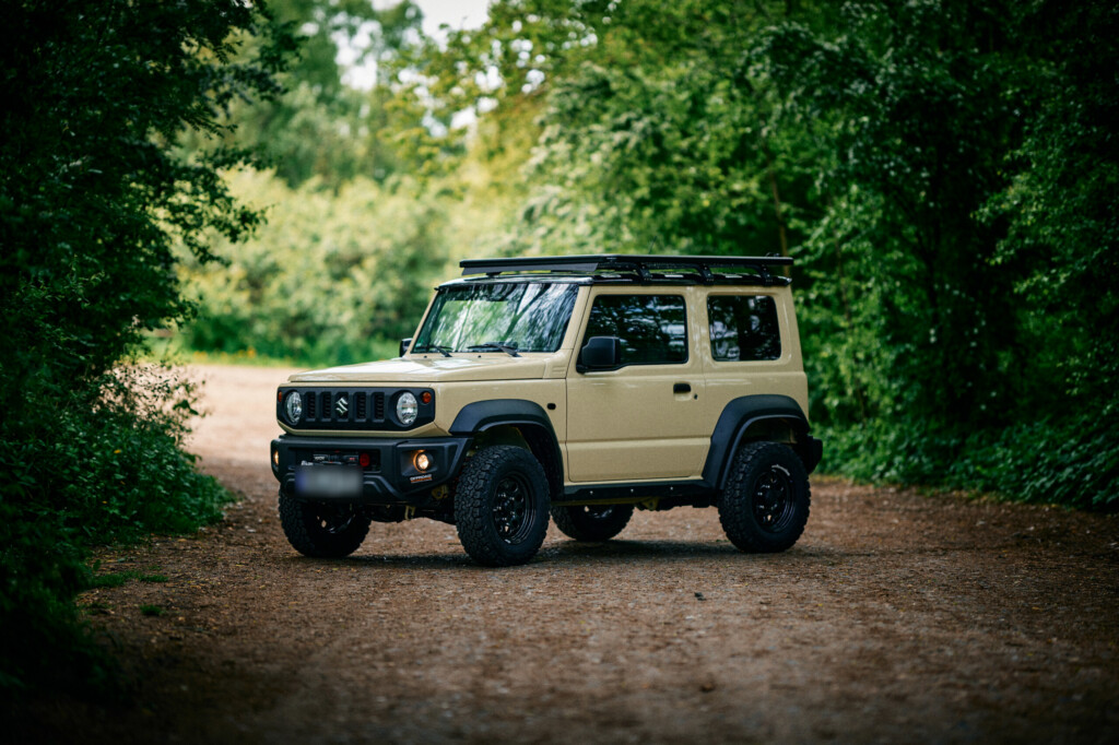 Suzuki Jimny GJ/HJ in Beige mit Dachträger auf Waldweg