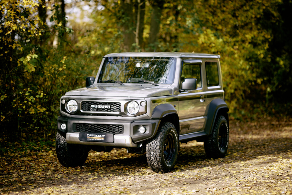 Suzuki Jimny HJ in Grau, höhergelegt, im herbstlichen Wald