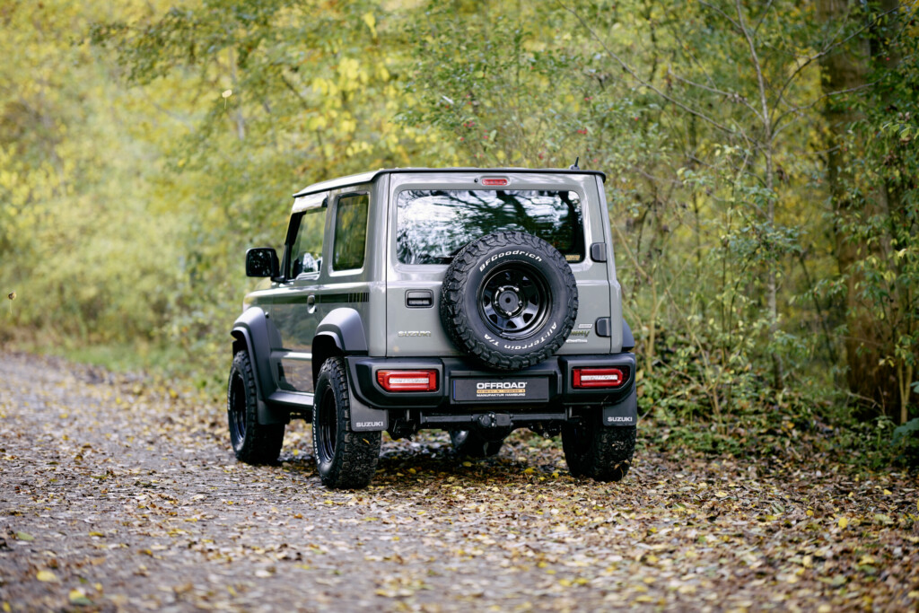 Suzuki Jimny HJ von hinten mit Reserverad auf Waldweg
