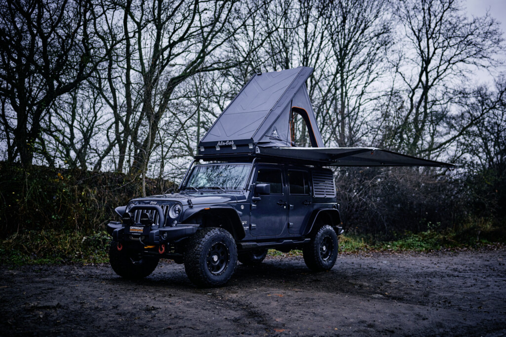 Jeep Wrangler JKU mit geöffnetem Dachzelt auf Waldweg