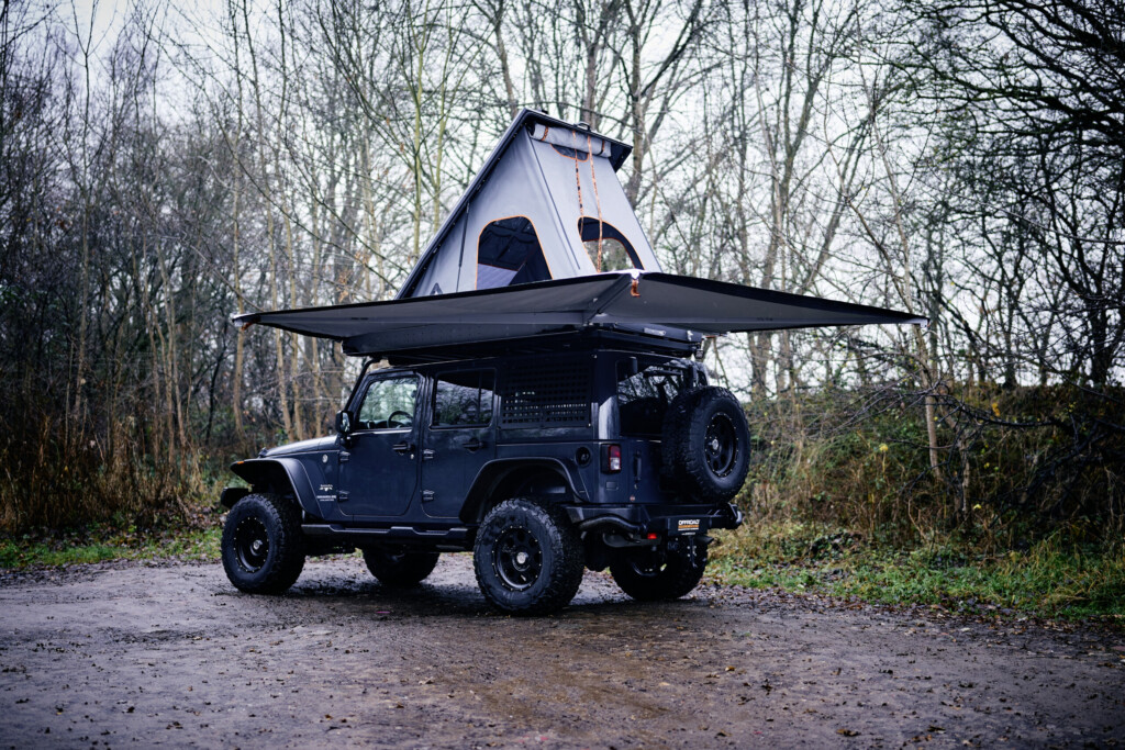 Jeep Wrangler JKU mit aufgestelltem Dachzelt und Markise auf Waldweg