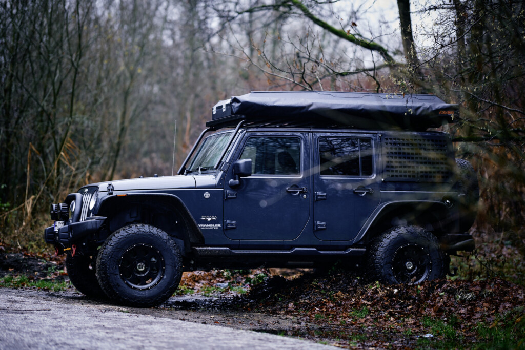 Jeep Wrangler JKU mit Dachzelt und Molleplatten im Wald, Seitenansicht