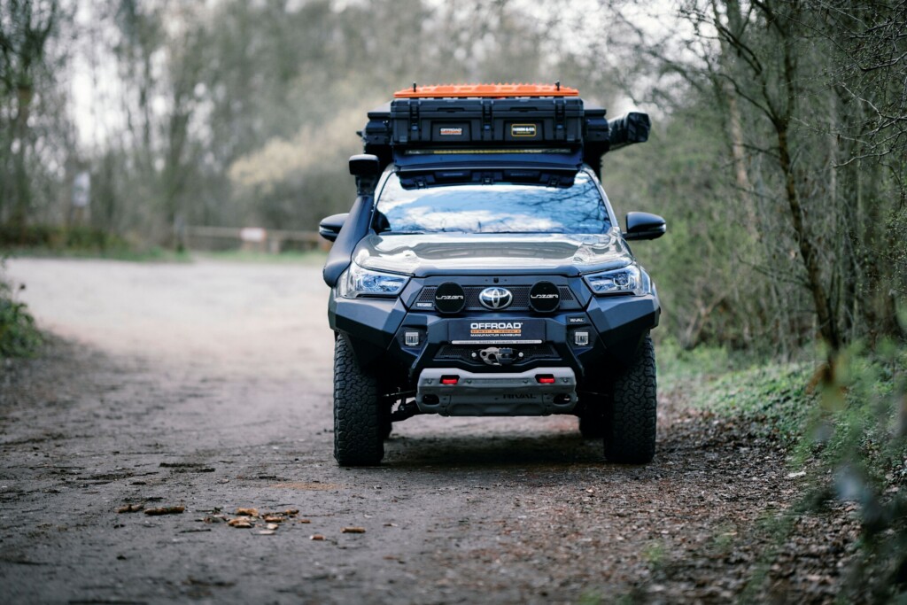 Toyota Hilux mit Dachträger, Schnorchel und OFFROAD-Frontstoßstange, Frontansicht auf einem Waldweg