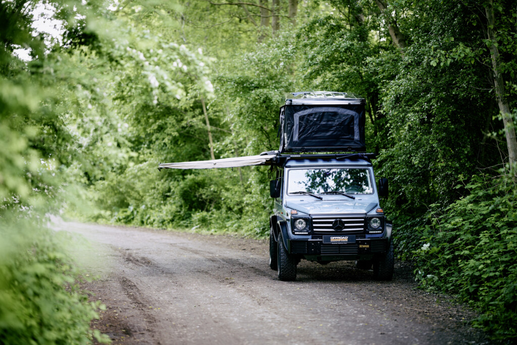 Mercedes G-Klasse mit Dachträger und Dachzelt auf Waldweg, Frontansicht