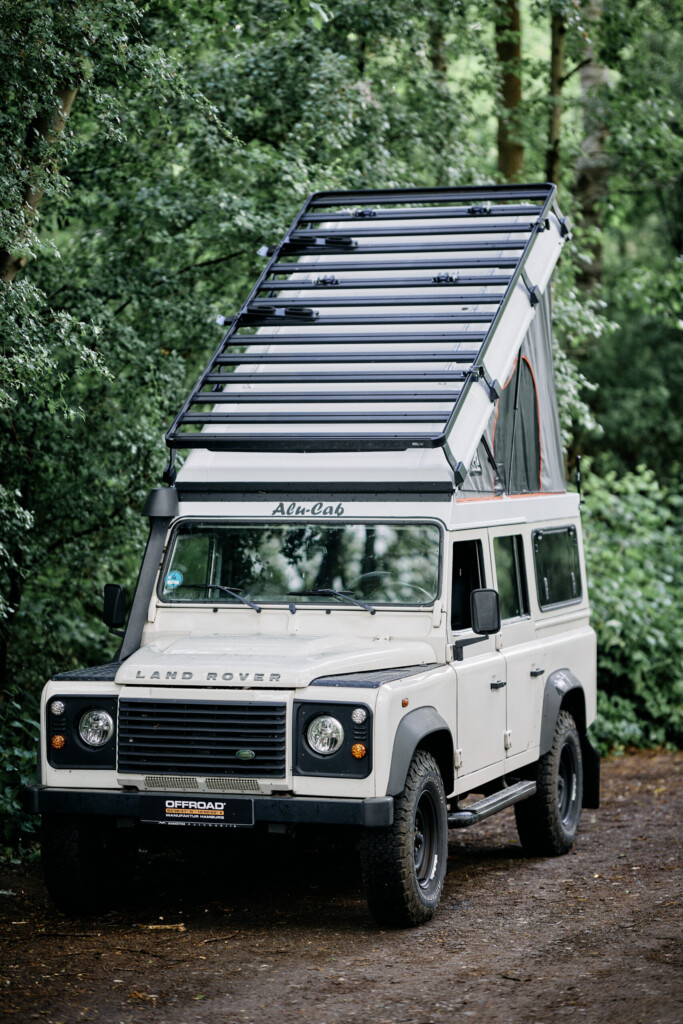 Land Rover Defender 110 mit Front Runner Dachträger im Wald