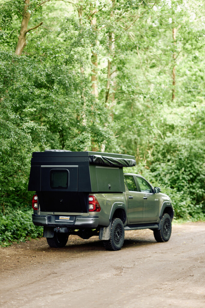 Toyota Hilux mit FiftyTen Wohnkabine auf Waldweg, Heckansicht