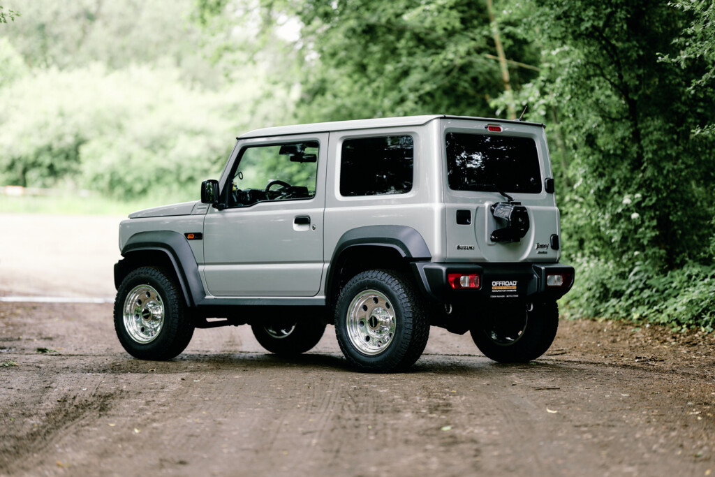 Suzuki Jimny HJ von hinten mit Geländereifen auf Waldweg
