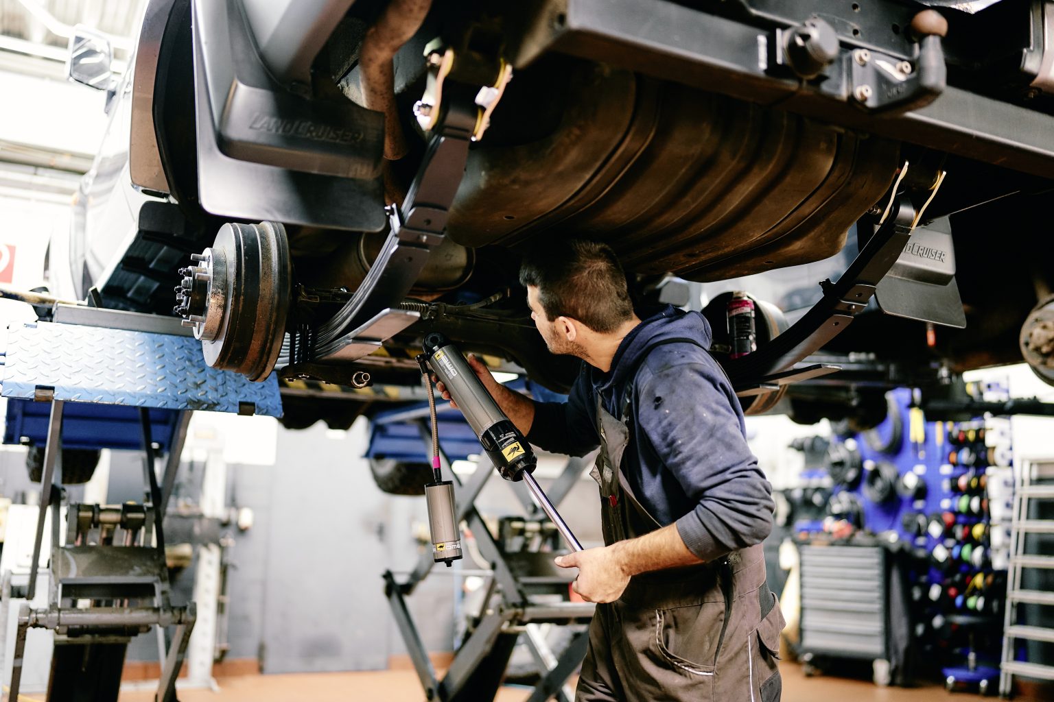 Mechaniker arbeitet unter einem Geländewagen auf der Hebebühne