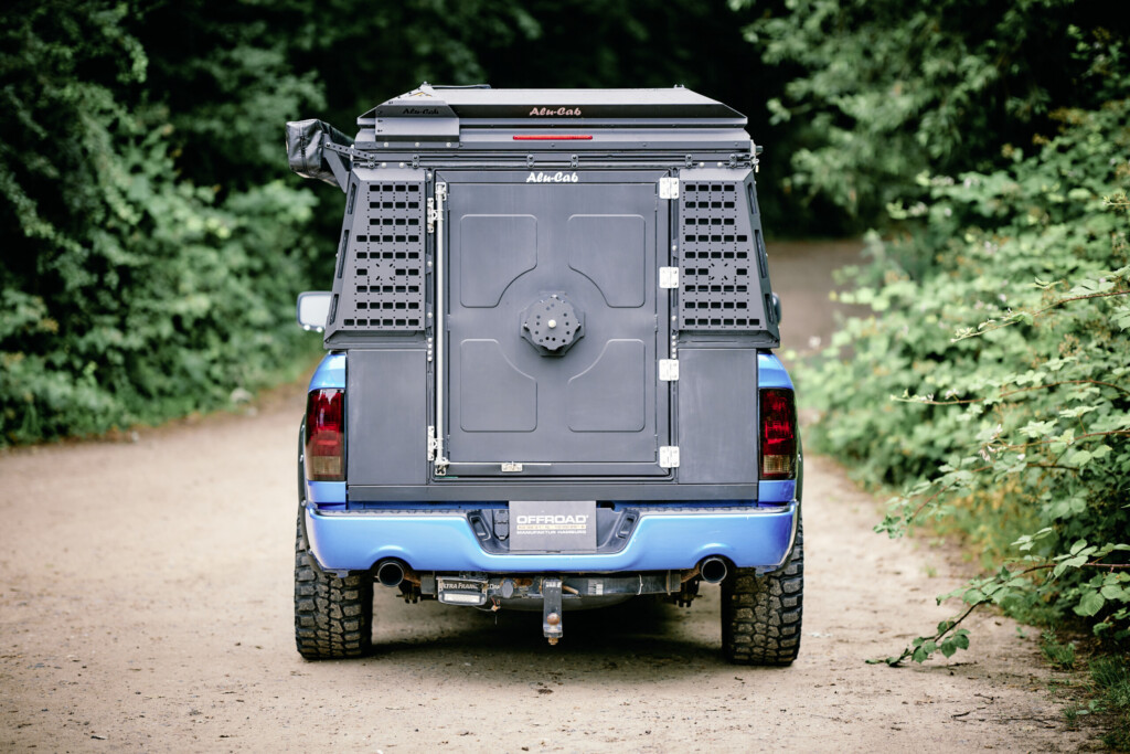 Rear view of the Dodge RAM 1500 with the Alu-Cab ModCAP tailgate closed on a forest track