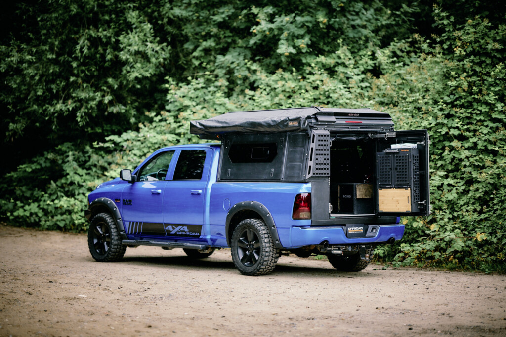 Dodge RAM 1500 with Alu-Cab ModCAP camper conversion, rear view on a forest track