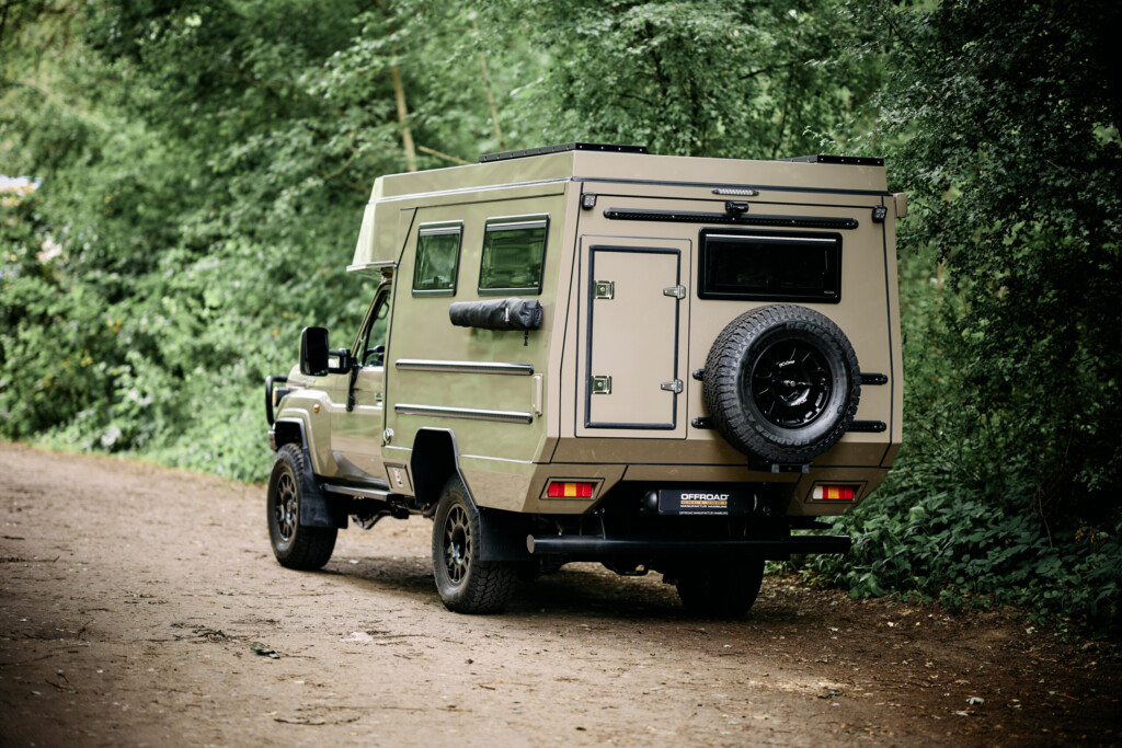 Toyota Land Cruiser J7 with camper cell, rear three-quarter view on a forest track