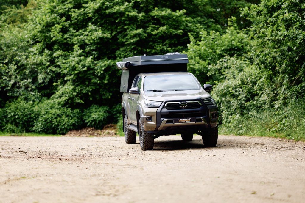 Toyota Hilux mit FiftyTen Wohnkabine auf einer Lichtung, Frontansicht