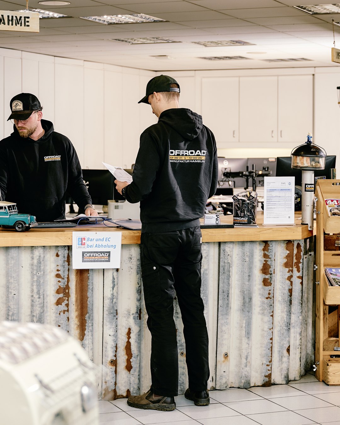 Annahme-Theke der Offroad Manufaktur Hamburg mit zwei Mitarbeitern