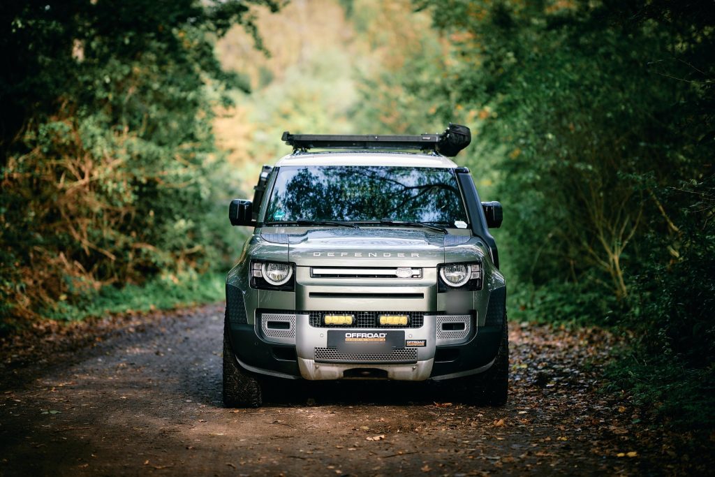 New Defender 110 von vorne auf einem Waldweg, Zusatzlicht aus