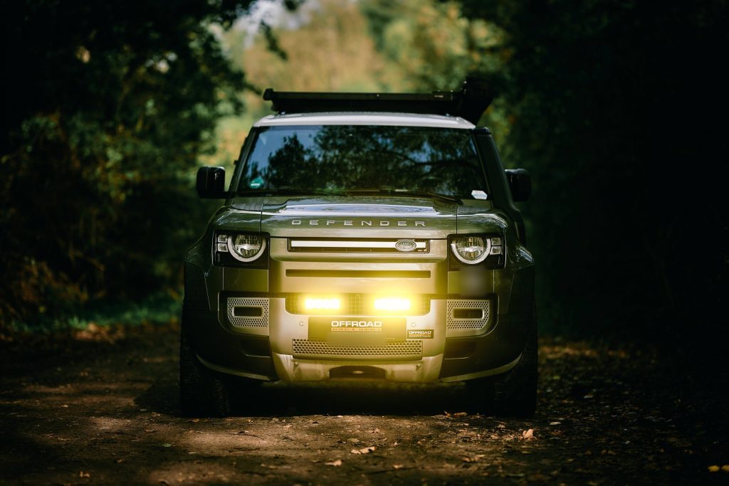 New Defender 110 von vorne mit eingeschaltetem gelbem Zusatzfernlicht