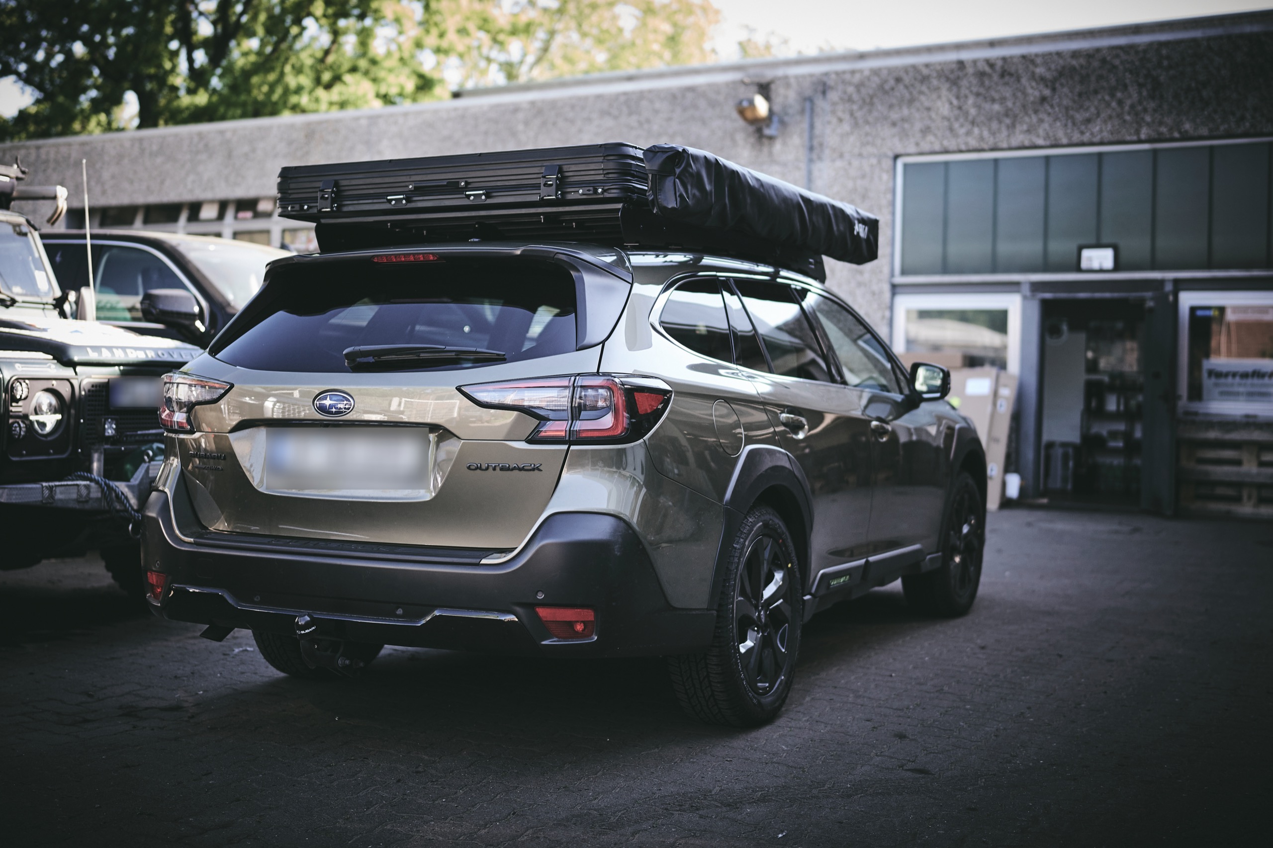 Subaru Outback mit Arcta Dachzelt, schräg von hinten auf dem Hof