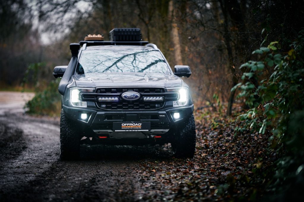 Ford Ranger Wildtrak mit eingeschaltetem Lazer Grill-Kit frontal im Wald