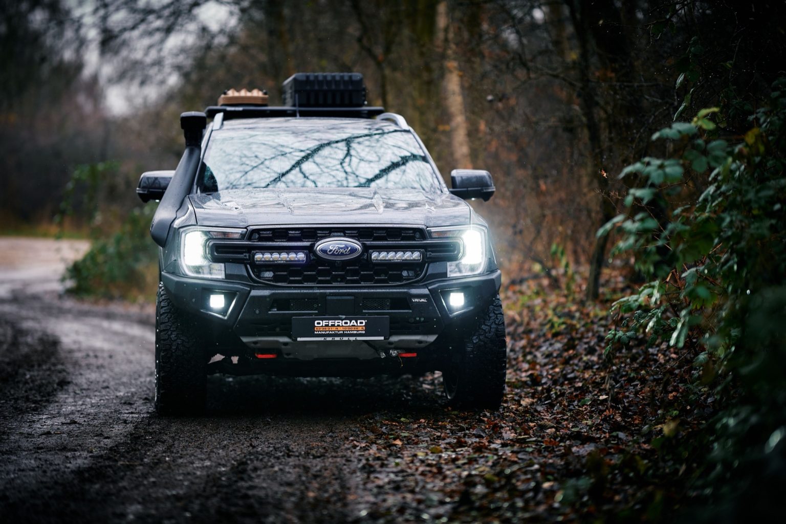 Ford Ranger Wildtrak mit eingeschaltetem Lazer Grill-Kit frontal im Wald